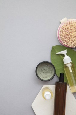 Gri arka planda yeşil yapraklı organik doğal kozmetik ürünü.