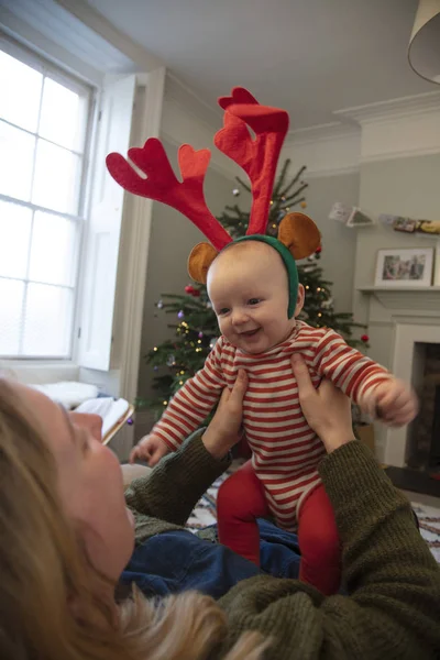 Χαριτωμένο μωρό φοράει γιορτινά κέρατα ταράνδου παίζει με τη μαμά τα Χριστούγεννα — Φωτογραφία Αρχείου