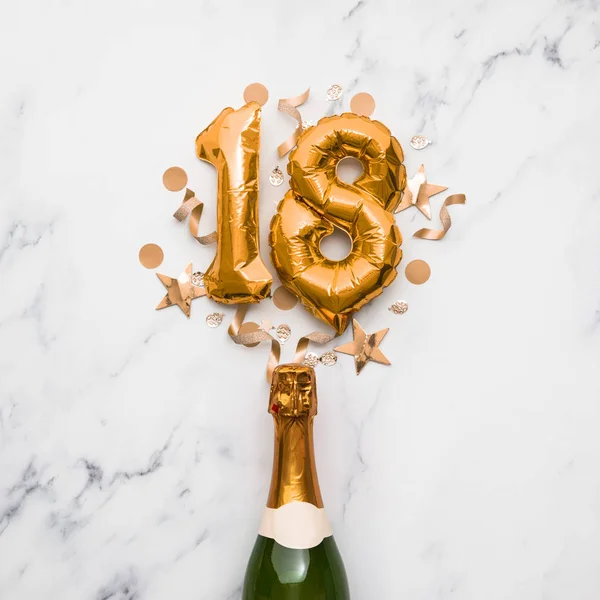 Bottiglia di champagne con palloncino numero 18 in oro. Concetto di anniversario del partito minimo — Foto Stock