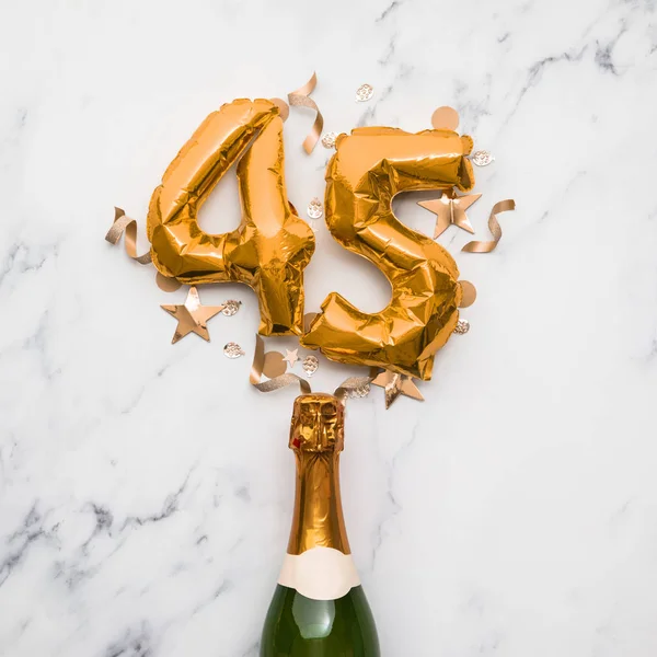 Bottiglia di champagne con palloncino numero 45 in oro. Concetto di anniversario del partito minimo — Foto Stock
