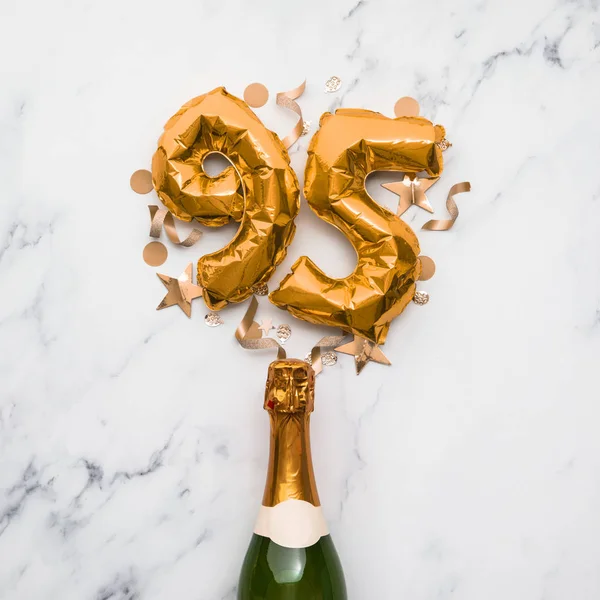 Champagne bottle with gold number 95 balloon. Minimal party anniversary concept