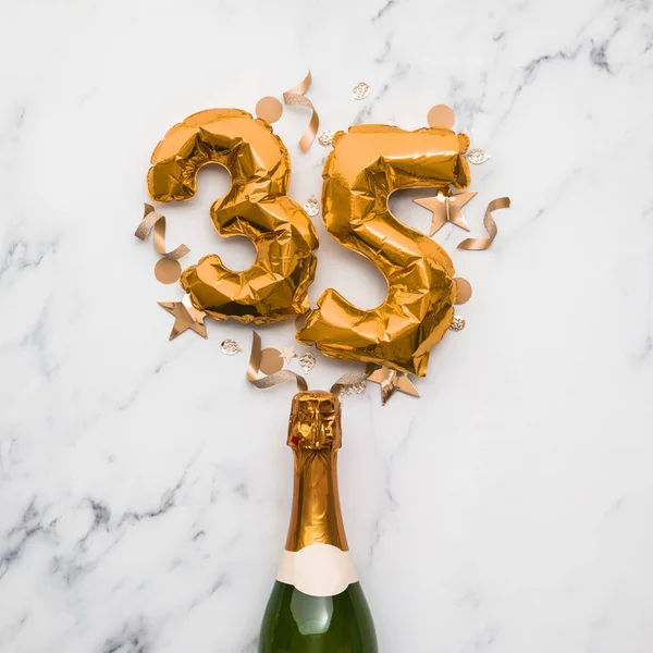 Bottiglia di champagne con palloncino numero 35 in oro. Concetto di anniversario del partito minimo — Foto Stock