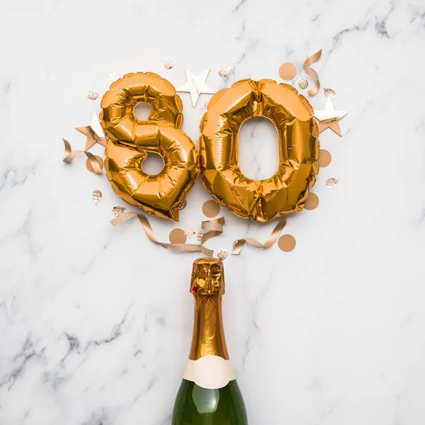 Champagne bottle with gold number 80 balloon. Minimal party anniversary concept