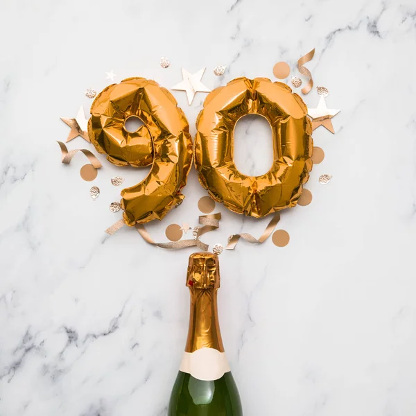 Champagne bottle with gold number 90 balloon. Minimal party anniversary concept