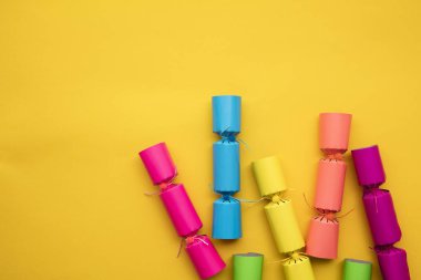 Sarı arka planda parlak renkli Noel krakerleri. Şenlikli aylak