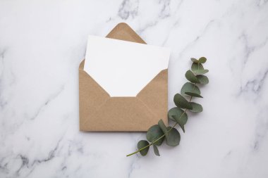 Boş beyaz kart ve okaliptüs yapraklı zarf. Boş davet.