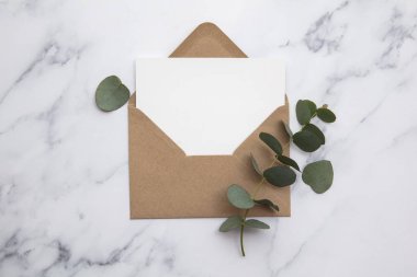 Boş beyaz kart ve okaliptüs yapraklı zarf. Boş davet.