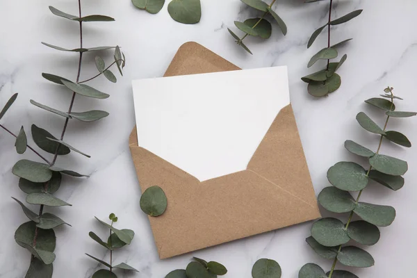 Üres fehér kártya és boríték eukaliptusz levelekkel. Üres meghívó. — Stock Fotó