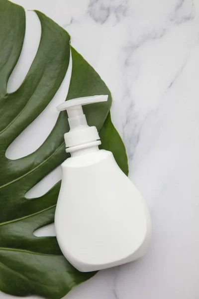 Productos cosméticos blancos en blanco sobre fondo de mármol con hoja de palma tropical — Foto de Stock