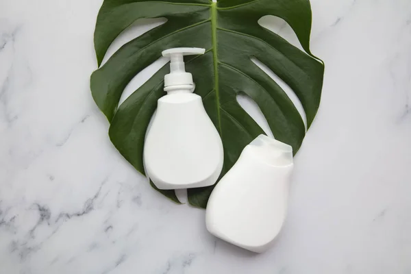 Produtos cosméticos brancos em branco sobre fundo de mármore com folha de palma tropical — Fotografia de Stock