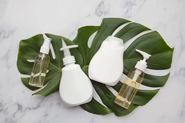 Productos cosméticos blancos en blanco sobre fondo de mármol con hoja de palma tropical — Foto de Stock