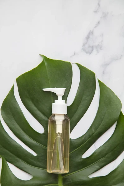 Kosmetické výrobky na mramorovém pozadí s tropickým palmovým listem — Stock fotografie