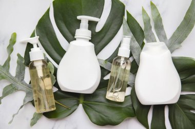 Mermer arka planda tropikal palmiye yapraklı kozmetik ürünleri