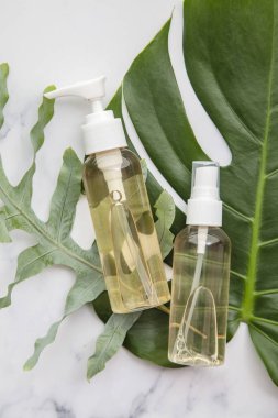 Mermer arka planda tropikal palmiye yapraklı kozmetik ürünleri