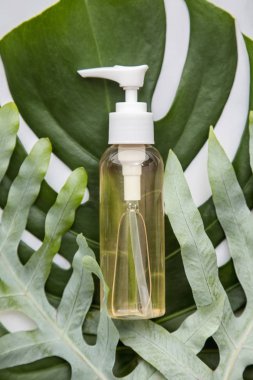 Mermer arka planda tropikal palmiye yapraklı kozmetik ürünleri