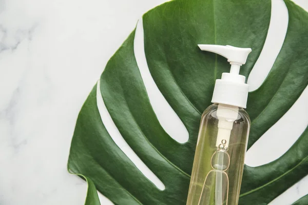 Productos cosméticos sobre fondo de mármol con hoja de palma tropical — Foto de Stock