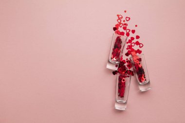 Valentines day shots. Shot glass with heart confetti on pastel pink background