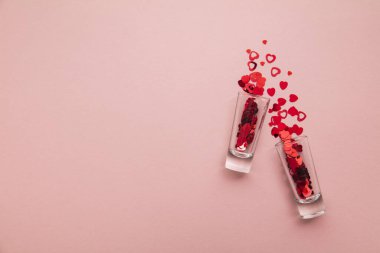 Valentines day shots. Shot glass with heart confetti on pastel pink background