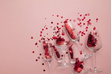Valentines day date night background. Drinks glasses with red heart confetti.