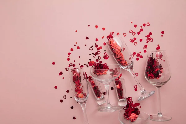 Valentines day date night background. Drinks glasses with red heart confetti.