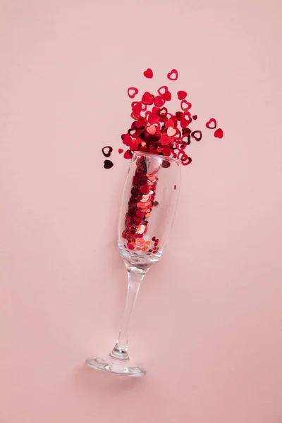 Valentines day date night background. Drinks glasses with red heart confetti.