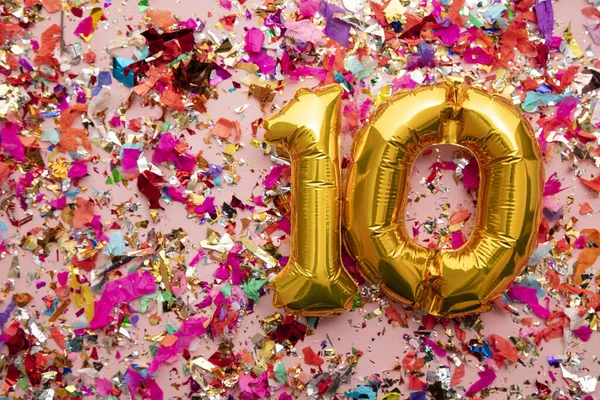 Globo de celebración de cumpleaños de oro número 10 sobre un fondo de brillo de confeti —  Fotos de Stock