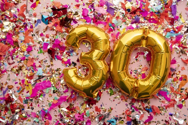 Number 30 gold birthday celebration balloon on a confetti glitter background — Stockfoto