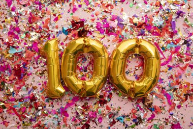 Number 100 gold birthday celebration balloon on a confetti glitter background