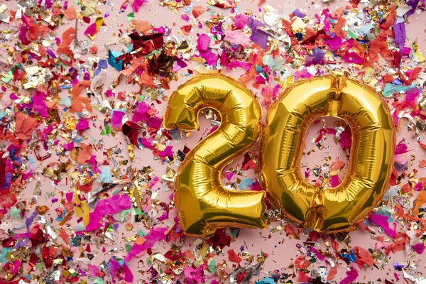 Number 20 gold birthday celebration balloon on a confetti glitter background — 스톡 사진