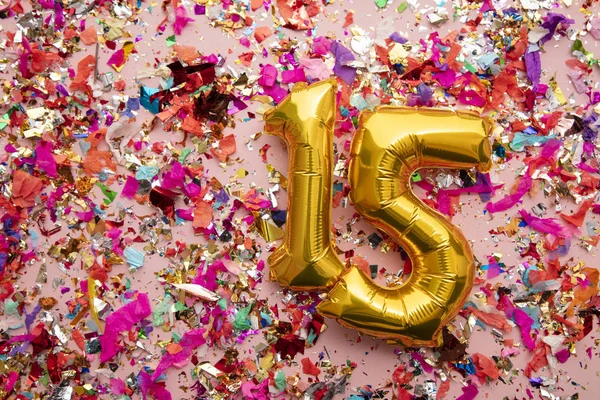 Número 15 ouro aniversário celebração balão em um fundo glitter confete — Fotografia de Stock
