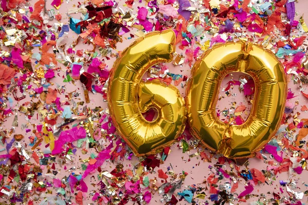 Number 60 gold birthday celebration balloon on a confetti glitter background