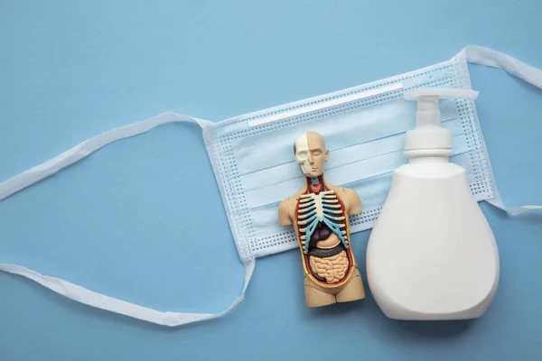 Beschermende medische masker en anti bacteriële handzeep op een blauwe achtergrond — Stockfoto