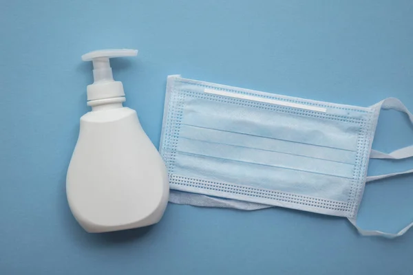 Beschermende medische masker en anti bacteriële handzeep op een blauwe achtergrond — Stockfoto