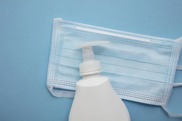 Beschermende medische masker en anti bacteriële handzeep op een blauwe achtergrond — Stockfoto