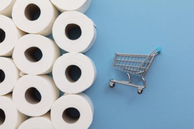 Mavi arka planda alışveriş arabası olan beyaz tuvalet kağıdı rulosu.