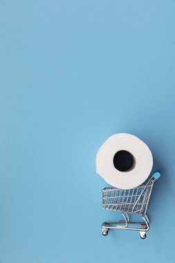 Mavi arka planda alışveriş arabası olan beyaz tuvalet kağıdı rulosu.