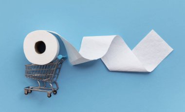 Mavi arka planda alışveriş arabası olan beyaz tuvalet kağıdı rulosu.