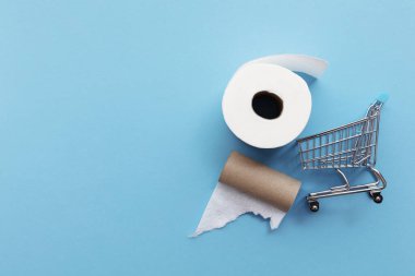 Mavi arka planda boş tuvalet kağıdı olan bir alışveriş arabası.