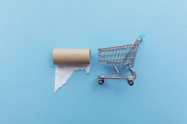 Mavi arka planda boş tuvalet kağıdı olan bir alışveriş arabası.
