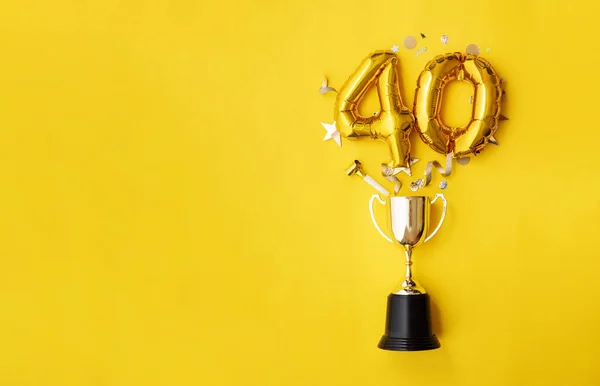 Número 40 aniversário de ouro balão celebração explodindo de um troféu vencedor — Fotografia de Stock