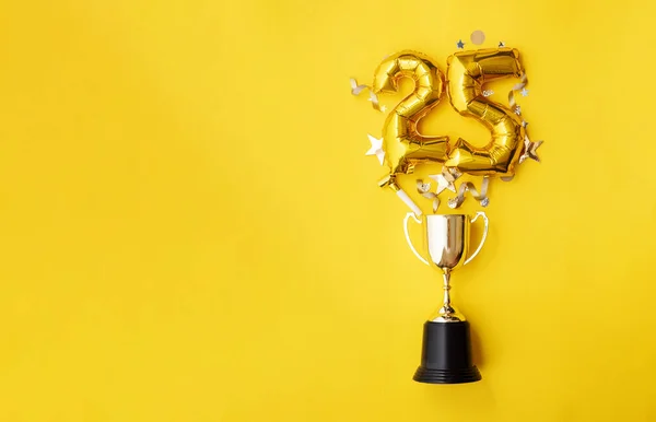Nummer 25 guld jubileum firande ballong exploderar från en vinnande trofé — Stockfoto