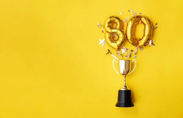 Globo de celebración número 80 aniversario de oro explotando de un trofeo ganador —  Fotos de Stock