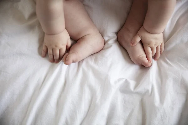 Close up of a babies hands and feet on a white bed sheet — Stock Photo, Image