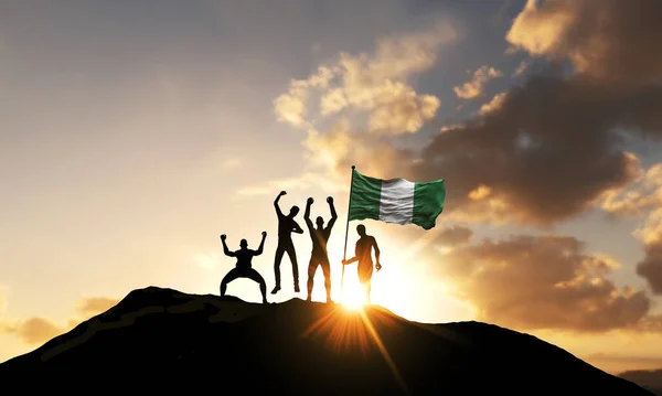 Un grupo de personas celebra en una cima de la montaña con la bandera de Nigeria. Renderizado 3D — Foto de Stock