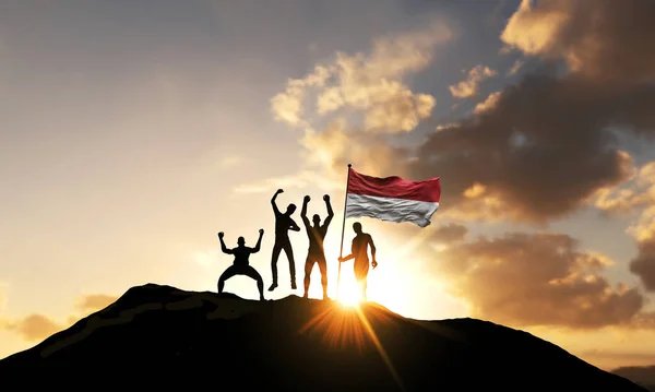 Un gruppo di persone festeggia sulla cima di una montagna con la bandiera indonesiana. Render 3D — Foto Stock