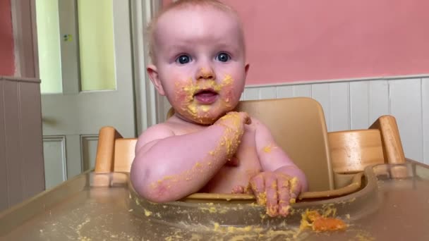 Счастливый младенец, покрытый едой во время отлучения от груди — стоковое видео