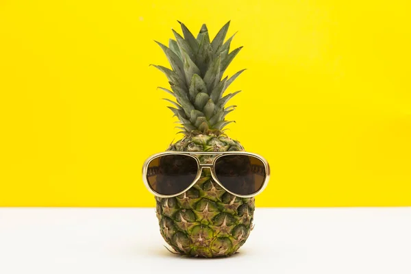 Sommar ananas frukt med solglasögon mot en ljust gul bakgrund — Stockfoto