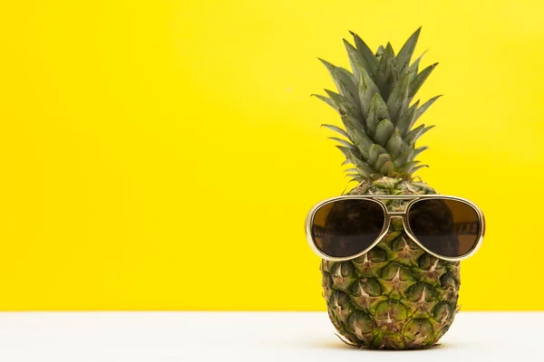 Sommar ananas frukt med solglasögon mot en ljust gul bakgrund — Stockfoto