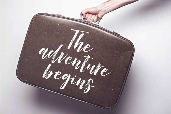 The adventure begins message on a vintage travel suitcase
