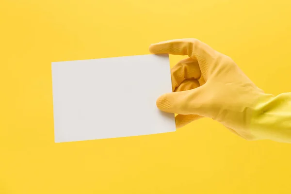 Handen i en gul rengöringshandske som håller ett tomt vitt kort — Stockfoto